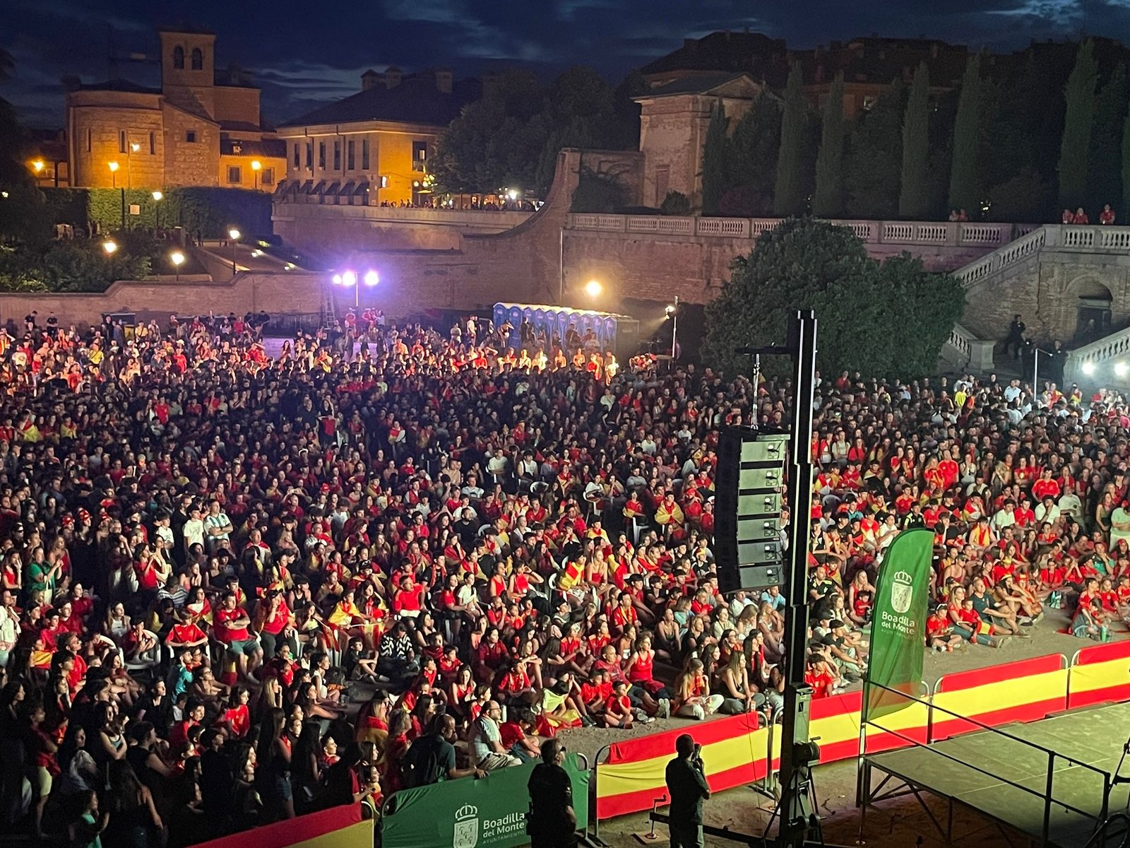 Imagen aérea noscturna que muestra un grupo de personas observando una pantalla led retrasmitiendo la final de la Eurocopa 2024 de España conta Inglaterra